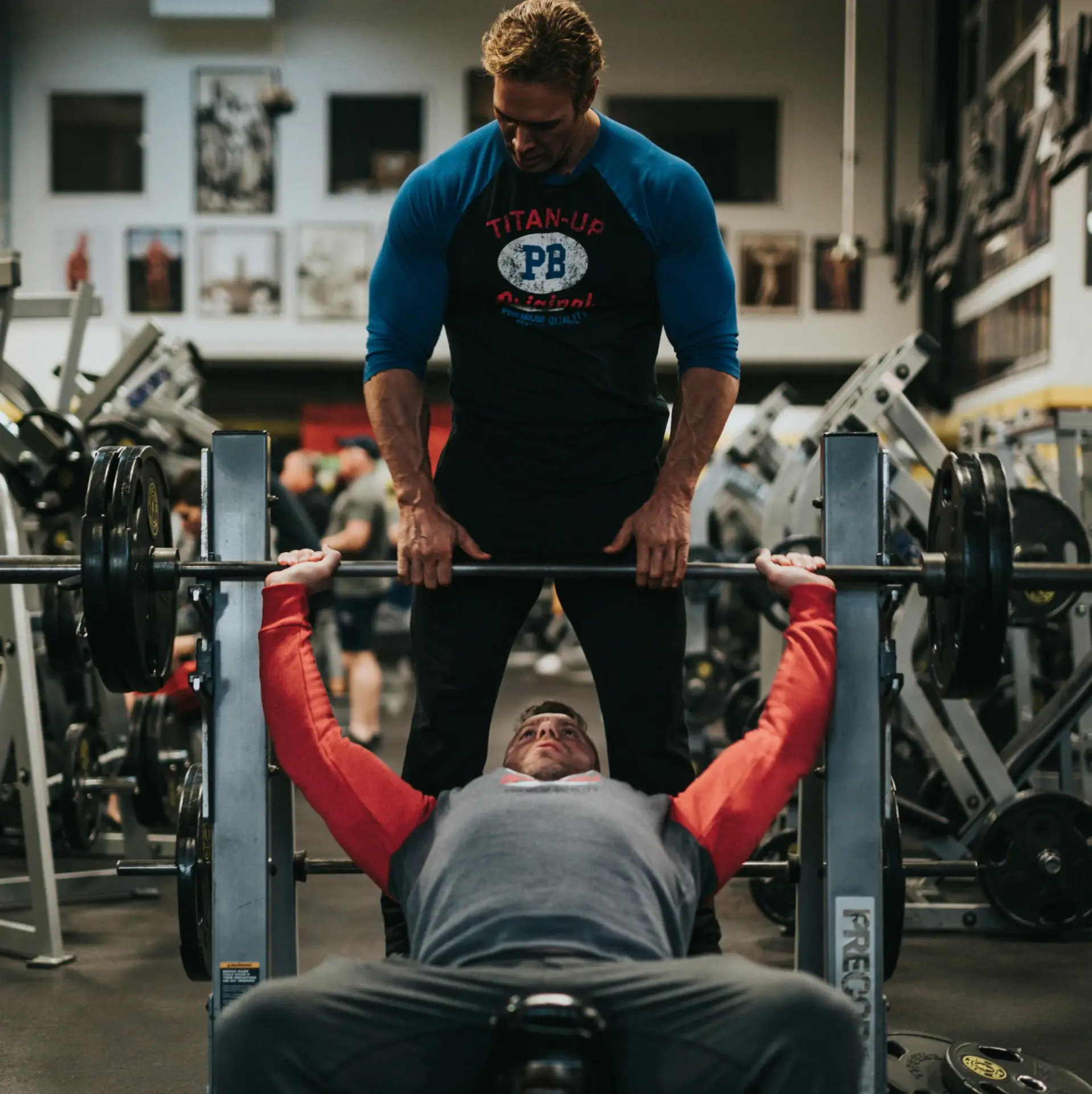 mężczyzna ćwiczy na ławeczce, wyciskanie sztangi w asyście trenera